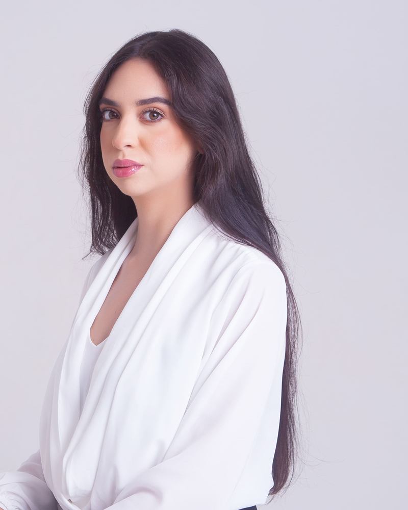 Retrato institucional de Isabella Ferreira, de blusa branca, com olhar firme