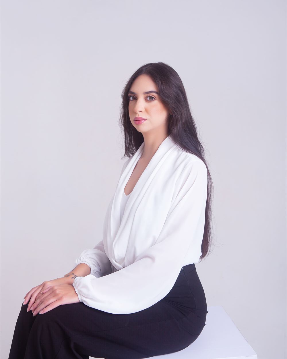 Isabella Ferreira sentada, de blusa branca, olhando para a câmera com expressão serena